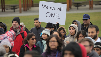People listen during a vigil in honor of Srinivas Kuchibhotla, an immigrant from India who was recently shot and killed in Kansas, at Crossroads Park in Bellevue, Washington