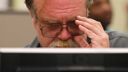 Man holds glasses while sitting at computer