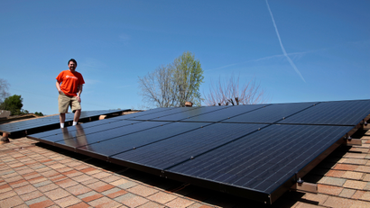 Mike Jones stands next to solar panels on the roof of his home in Los Angeles, California March 18, 2011. Jones leased 22 solar panels from solar electric system company Sungevity. The panels would have cost him $13,000, but the 20-year lease cost $4,000. The first month after the panels were installed Jones' electricity bill went down from $160 to $11.