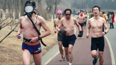 A half-naked participant wears a gas mask as he takes part in the "Guangzhu (naked) Run" with others on a hazy winter morning at the Olympic Forest Park in Beijing, February 23, 2014. Beijing's running enthusiasts joined this event, which required them to run wearing only their underwear, as a way to promote environmentally-friendly lifestyles, on Sunday morning under an orange alert of air pollution, local media reported. REUTERS/China Daily