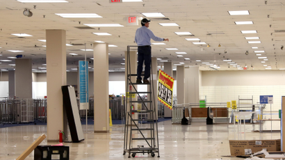 A worker removes sale banners inside a closed Sears department store