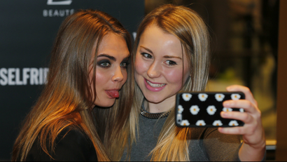 Model Cara Delevingne (L) poses for a selfie with a fan during a photo call at Selfridges department store in London.