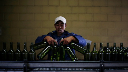 A worker loads wine bottles onto a conveyer belt at the Rostberg bottling plant near Cape Town, November 29, 2012.