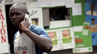 A Kenyan man talks on his mobile while walking through the high density suburb of Kangami in Nairobi, Kenya on 26 March 2008. The Kenyan government plans to sell 25 per cent of its stake in the highly profitable mobile operator Safaricom by holding east Africa's largest ever IPO which is scheduled to begin selling shares on 28 December 2008.