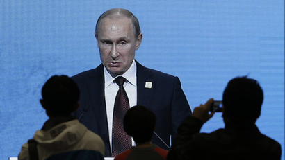 Journalists watch a live broadcast on an electronic screen showing Russia's President Vladimir Putin giving a speech during the APEC CEO Summit in Beijing, November 10, 2014.