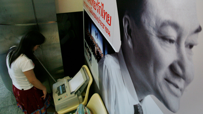 A reporter uses a fax near the portrait of ousted prime minister Thaksin Shinawatra displayed on the walls of the Thai Rak Thai party headquarter in Bangkok