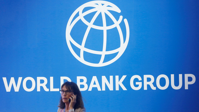 A woman on the phone stands near a logo of World Bank at the International Monetary Fund