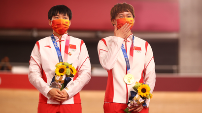 Gold medallists Bao Shanju and Zhong Tianshi wear protective face masks and pose with badges of the late Chinese chairman Mao Zedong pinned to their tracksuits