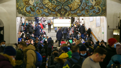 People crowd the stairwell of an underground subway station in Kyiv, Ukraine. The station is decorated with mosaic tiles in green, yellow and blue