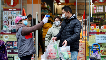 Worker measures body temperature of people leaving a supermarket in Qingshan district following an outbreak of the novel coronavirus in Wuhan