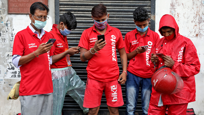 Delivery workers of Zomato wait to collect orders outside a restaurant in Kolkata