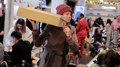 A woman holds a box aloft amid a sea of holiday shoppers at a Macy's department store.