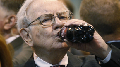 Berkshire Hathaway CEO Warren Buffett drinks a bottle of Coca Cola during at a trade show at the company's annual meeting in Omaha, Nebraska May 3, 2014. Warren Buffett's Berkshire Hathaway Inc on Friday said quarterly profit declined 4 percent, falling short of analyst forecasts, as earnings from insurance underwriting declined and bad weather disrupted shipping at its BNSF Railway unit. REUTERS/Rick Wilking (UNITED STATES - Tags: BUSINESS)