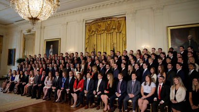 US President Donald Trump stands with departing White House interns as he poses for a photograph with them