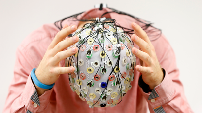 Test person Thiel poses with an electroencephalography cap which measures brain activity, at the Technische Universitaet Muenchen in Garching