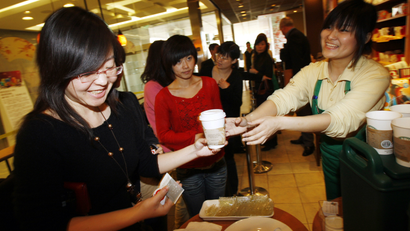 A Starbucks staff member hands out free coffee to customers at an event to mark the 10th anniversary of Starbucks' launch in China, at the the company's original outlet in Beijing Wednesday, Jan. 14, 2009. The Coffee chain Starbucks has started producing coffee grown by farmers in China and hopes to bring the blend to stores all over the world.