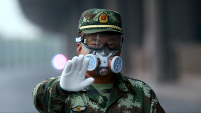 A paramilitary policeman wearing a mask gestures to the photographer to stop as he blocks a road leading to the evacuated residential area and explosion site, at Binhai new district in Tianjin, China, August 17, 2015.