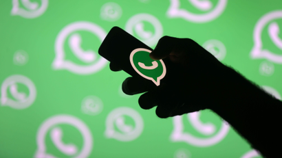 A man poses with a smartphone in front of displayed Whatsapp logo in this illustration