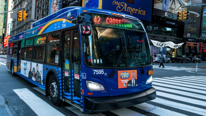 blue bus crosses a pedestrian crosswalk in downtown New York