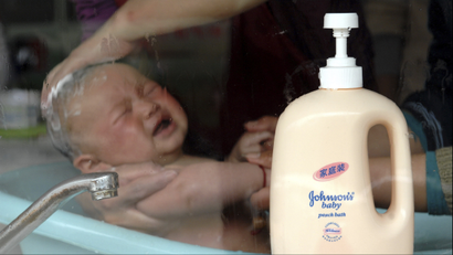 A baby is bathed as a bottle of Johnson & Johnson's baby product stands in foreground at a baby care center in Xiangfan, in central China's Hubei province, on Monday, March 16, 2009. Shanghai's food and drug safety agency said it is testing Johnson & Johnson baby products following allegations they contain potential carcinogens. (AP Photo