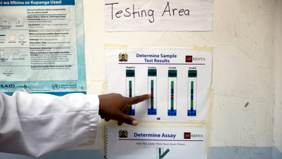 A finger points to a poster of test results.