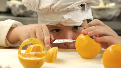 Zeke Andreassen, 11, cuts an orange into a decorative basket in the kitchen of the Vermont Kids Culinary Academy during a residential cooking summer camp in Highgate