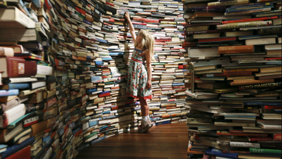Leona, 7, poses inside a labyrinth installation made up of 250,000 books titled "aMAZEme" by Marcos Saboya and Gualter Pupo at the Royal Festival Hall in central London July 31, 2012.