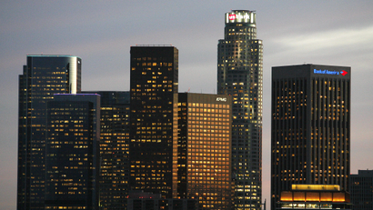 a city skyline at dusk with several office skyscrapers with lights on