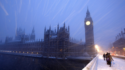 Pedestrians walk across Westminster Bridge as snow falls in central London