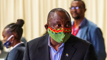 An image of South Africa's president wearing a colorful face mask as he listens in on a discussion in a covid-19 treatment facility