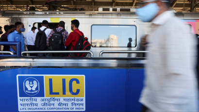 A man walks past a Life Insurance Corporation of India (LIC) logo at a metro station in Mumbai