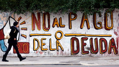 A woman walks past a graffiti that reads "No to the debt payment" in Buenos Aires, July 28, 2014. Time is running out for Argentina to pay "holdout" investors suing Latin America's No. 3 economy for full payment on their bonds, or reach a deal that buys more time to avert a default.
