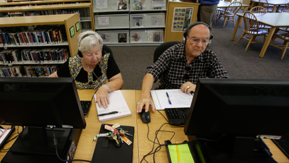 In this Wednesday, Sept. 10, 2014 photo, retirees Edna, left, and Pedro Cortes make use of computers at a branch of the Citrus County Library, in Beverly Hills, Fla. In Citrus County, more than a third of residents are senior citizens, the sixth-highest rate in the nation.(AP Photo/John Raoux)