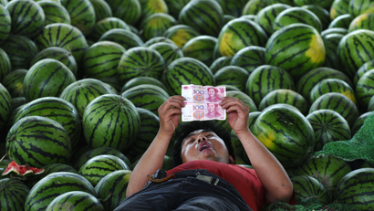 A watermelon vendor looks at yuan banknotes at a market in Changzhi, Shanxi province June 21, 2010.
