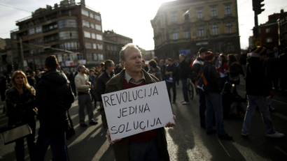 An anti-government protester holds a placard that reads "Revolution is the only solution" as protesters block Alipasina street during protests in Sarajevo in Feb. 2014
