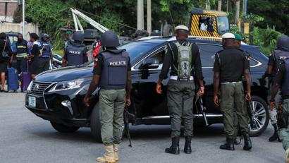 Police officers in Nigeria stand close to a road on which a car is passing