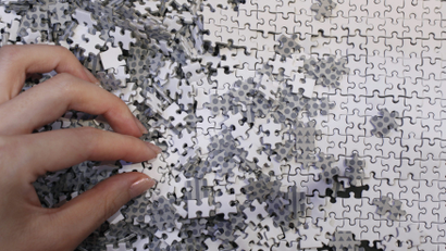A partially assembled puzzle with white and grey pieces.