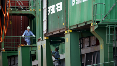 Workers are pictured between containers atop a cargo ship at a port in Tokyo August 19, 2015.