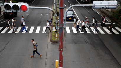 People walk on a crosswalk at a shopping district in Tokyo