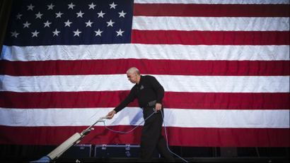 Worker cleans a stage in front of a US flag