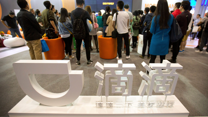 Visitors look at a display booth for Chinese ride-hailing service Didi Chuxing at the Global Mobile Internet Conference (GMIC) in Beijing, Thursday, April 27, 2017.
