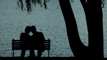 A pair of Chinese lovers rest beside a lake at a park in Beijing