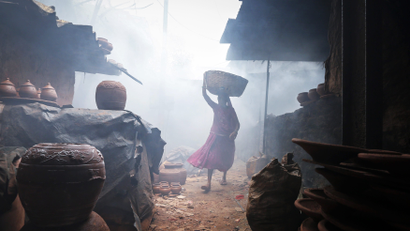 A woman potter carries earthen pots through traditional pottery kilns in Dharavi, one of Asia's largest slums in Mumbai