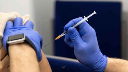 a person wearing gloves holding a needle in front of somone's arm