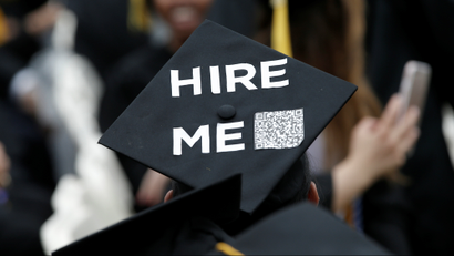 An image of a student where a graduation cap that say "hire me".