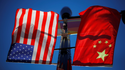 US and China flags fly on a lamppost.