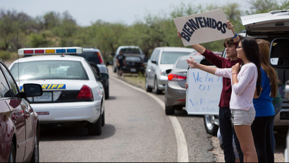 Marcus Martinez of Oracle, Arizona, holds up a sign in Spanish that reads "Welcome" as he and other members of his family watch as vehicles leave a demonstration against the arrival of undocumented immigrants in Oracle, Arizona July 15, 2014. In a scene reminiscent of similar protests in California, about 65 demonstrators gathered at a fork in the road near the small town of Oracle to complain that the federal government's response to a surge of new arrivals from Central America was putting their communities at risk.