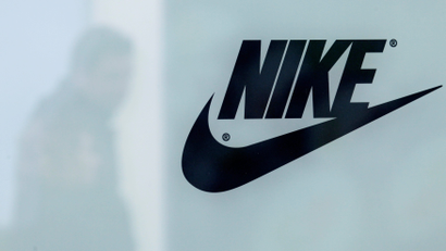 A customer is reflected in a shop window decorated with Nike store logo