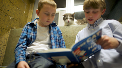 two kids reading with their cat