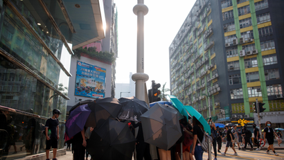 Protesters use umbrellas to shield themselves as people damage smart lamppost in Ngau Tau Kok in Hong Kong.